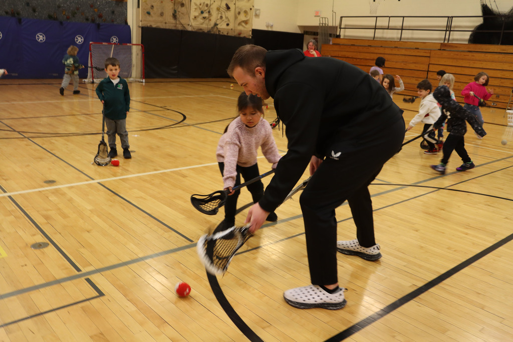 A player shows a student how to use their stick.