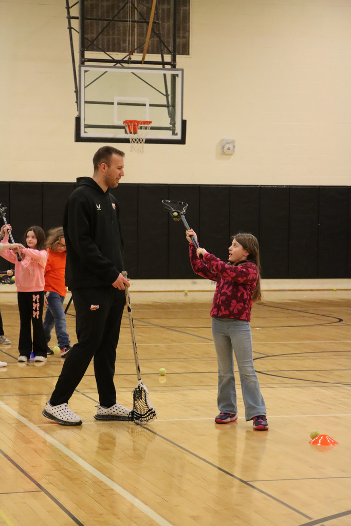 A player shows a student how to use their stick.
