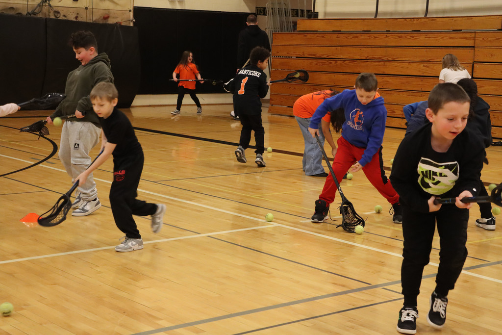 students use their sticks to pick up a ball.