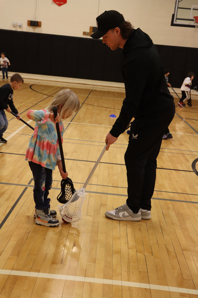 A player shows a student how to use their stick.