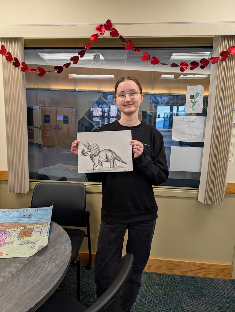 high school student posing with her dinosaur drawing