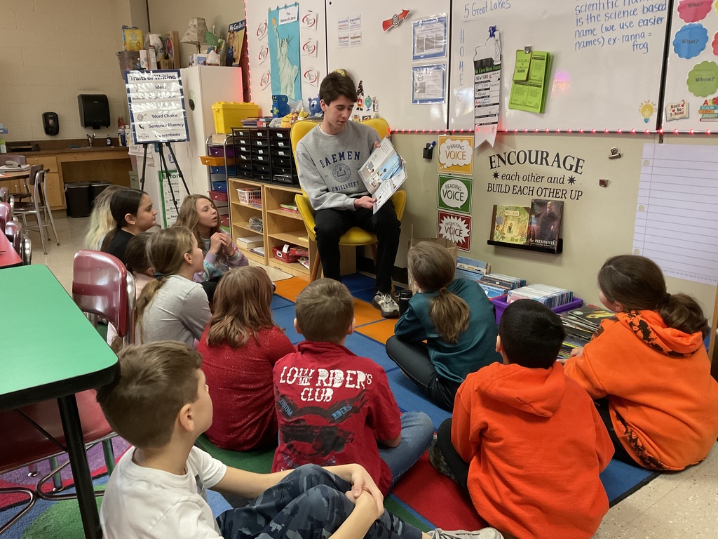 Students look on as Sam Bowers reads a book