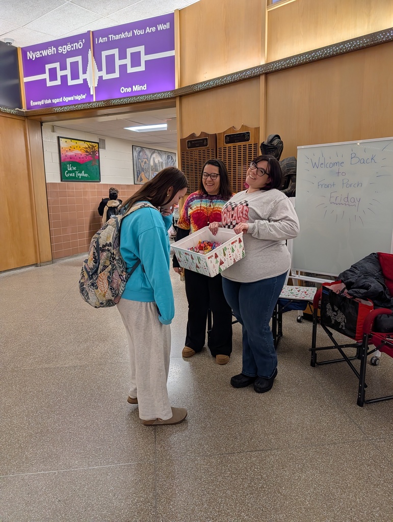 A girl picks a positive affirmation from the bucket as Mrs. Austin and Ms. Laurenzi smile
