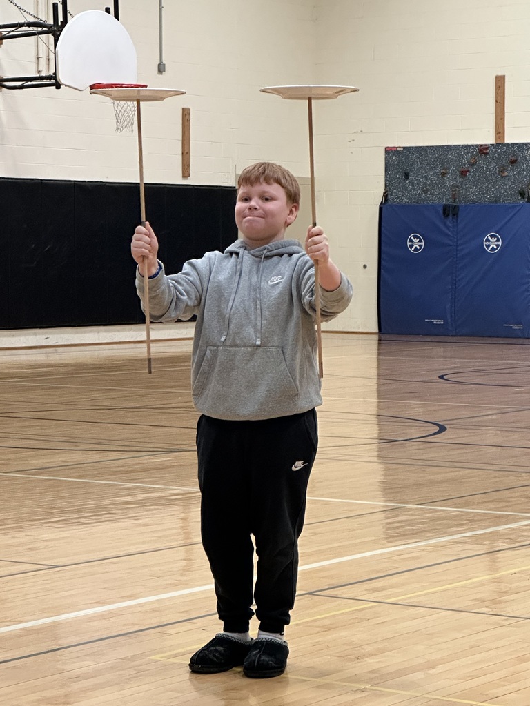 Boy balancing plate on stick in each hand