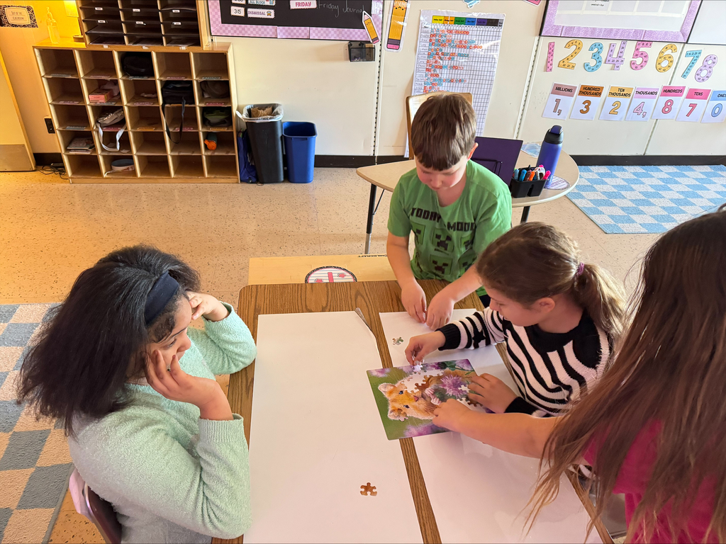 two girls and a boy working on a puzzle