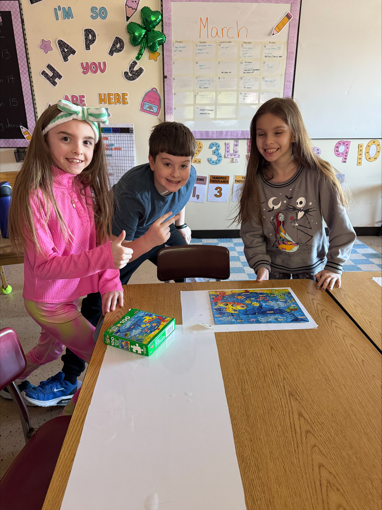 two girls and a boy smiling over a completed puzzle