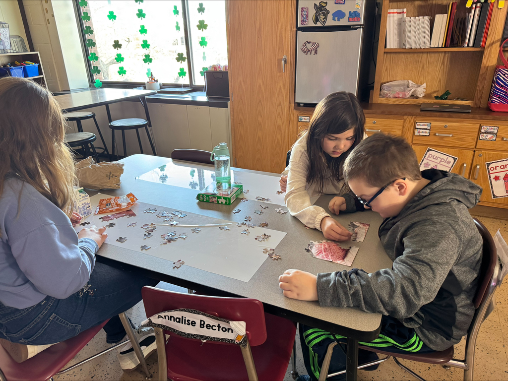 students at a table with puzzle pieces scattered