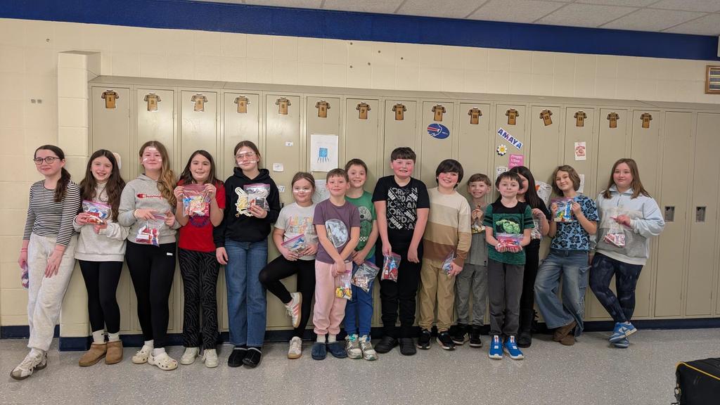 Class in front of lockers smiling with candy bags