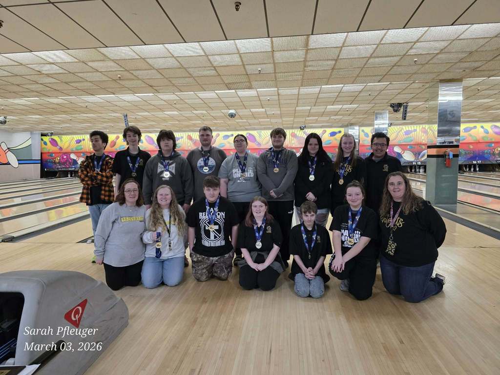 Unified bowling team members pose in front of bowling lanes