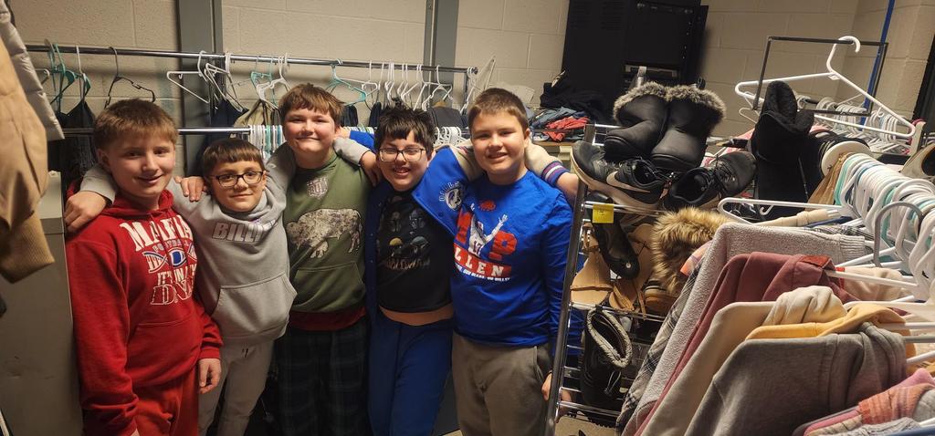 5 middle school boys smiling in the clothing closet room