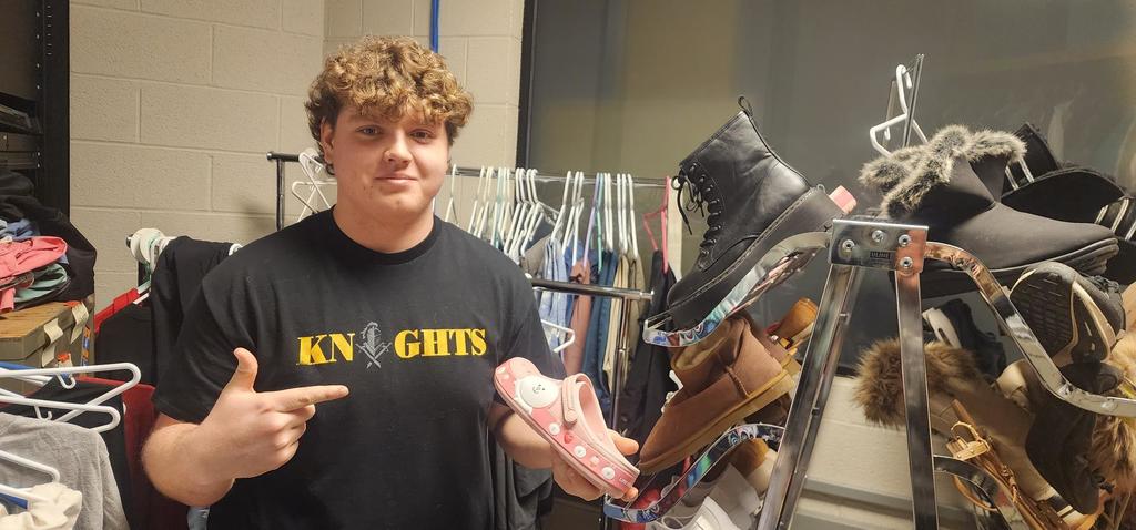 A boy smiliong holding shoes