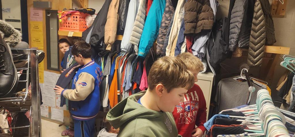 middle school boys sorting through clothing racks