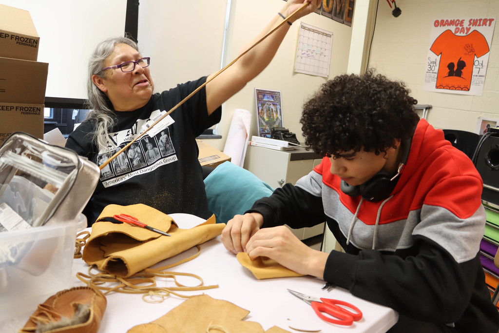 a student sews a moccasin with the instructor