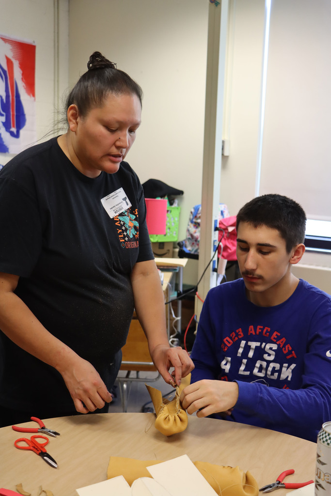 the instructor shows a student a stitch.
