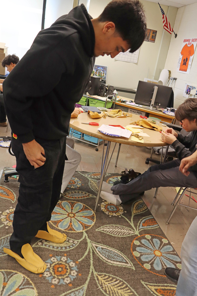 a student tries on his moccasins.