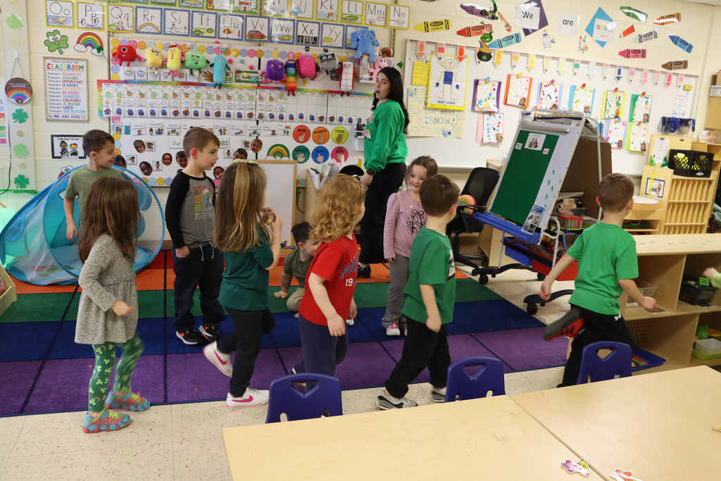 students dance behind the teacher in a circle