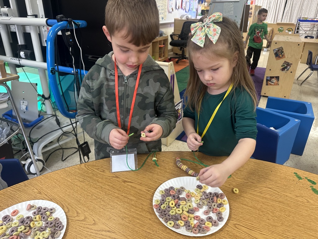 A boy and girl make cereal necklaces