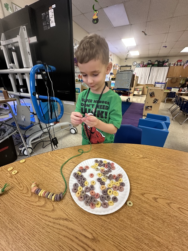A boy makes a necklace from cereal and yarn