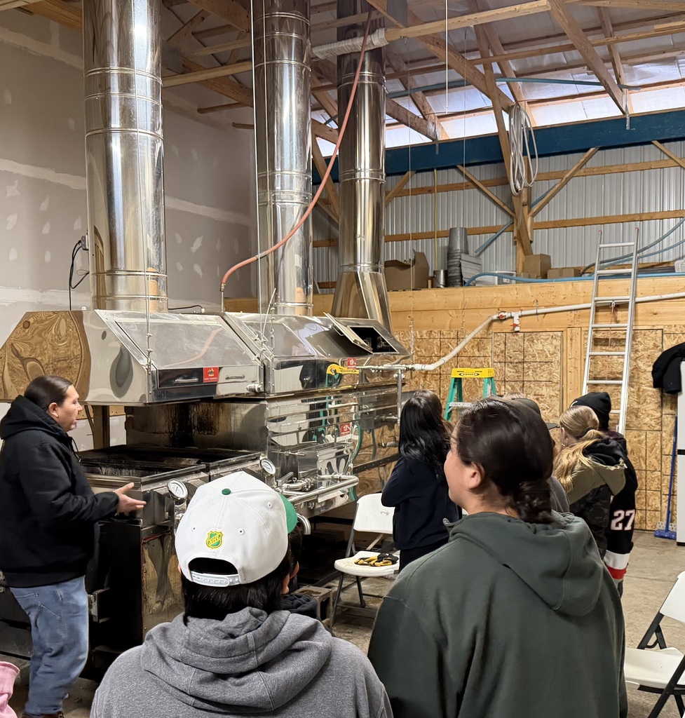 Farm worker shows students maple boiling tanks