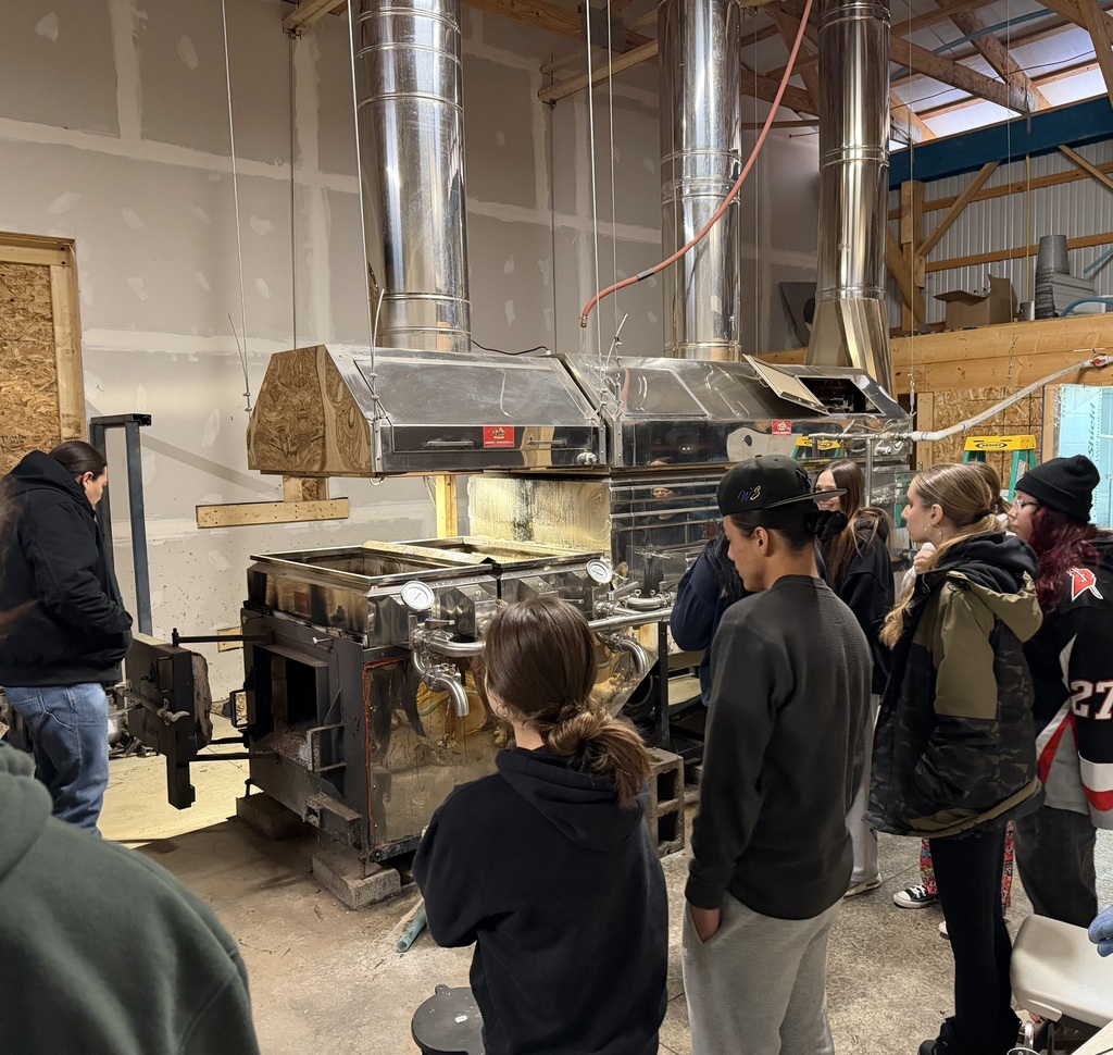 Farm worker shows students maple boiling tanks