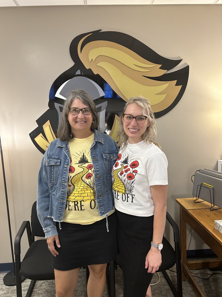 Mrs. Smith and Mrs. Nebauer smiling with the knight logo in the background