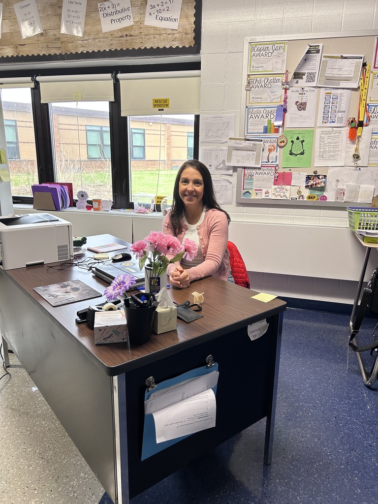 Mrs. Lawrence in a pink sweater at her desk