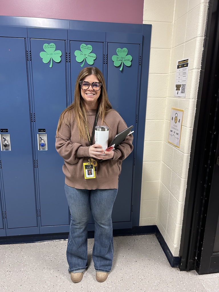 Mrs. Hamms smiles in front of blue lockers