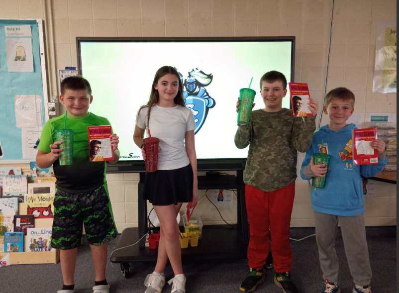 Spelling Bee winners smiling and holding their prizes