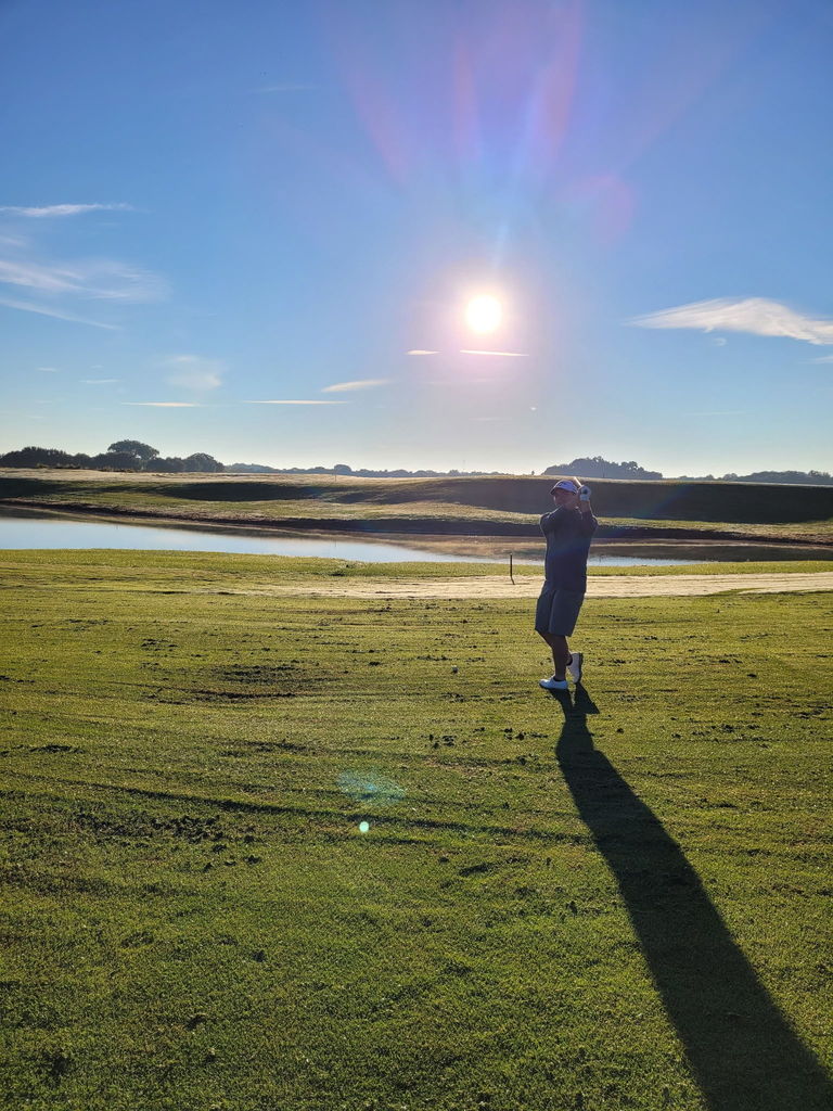 Jake swinging a gold club on the green