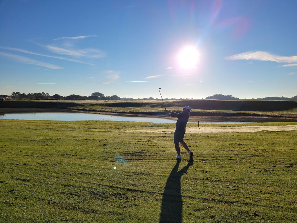Jake swinging a gold club on the green