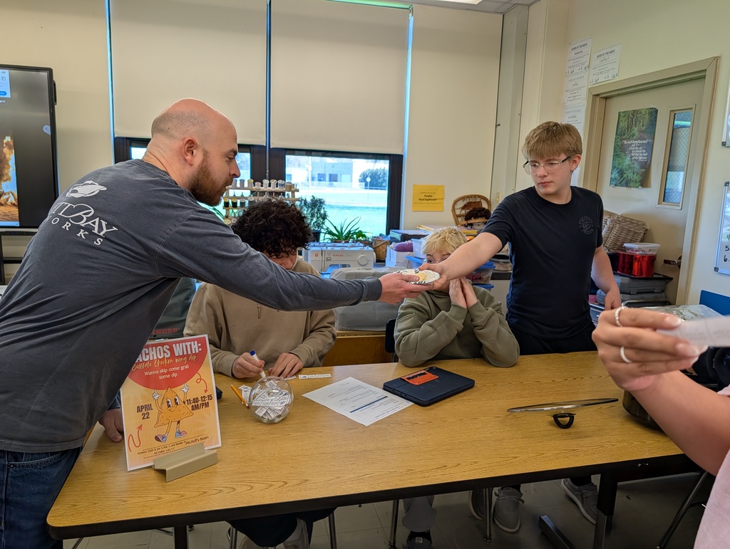 students handing a teacher a bowl of wing dip