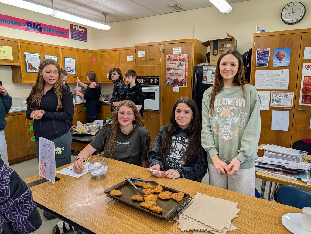 students smiling at table with tray of fried dough