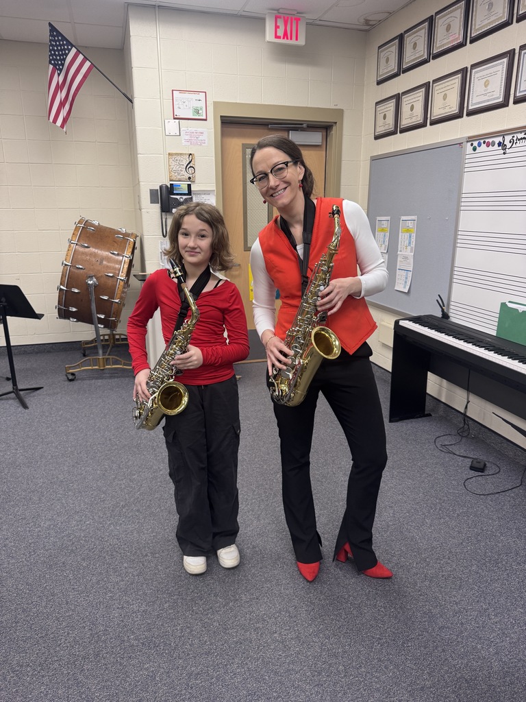 Dr. Ralston and female student waering red and holding saxophones
