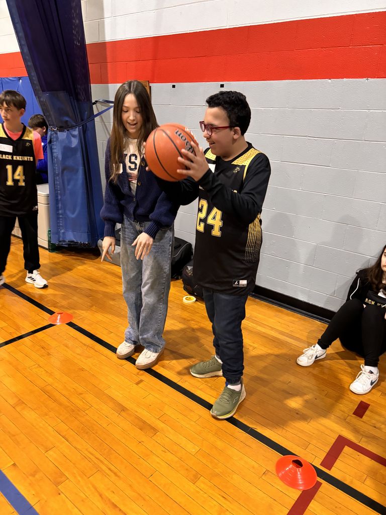 A student helps another dribble. 