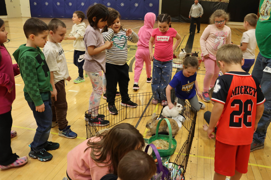 A group of kindergartners pet the rabbits. 