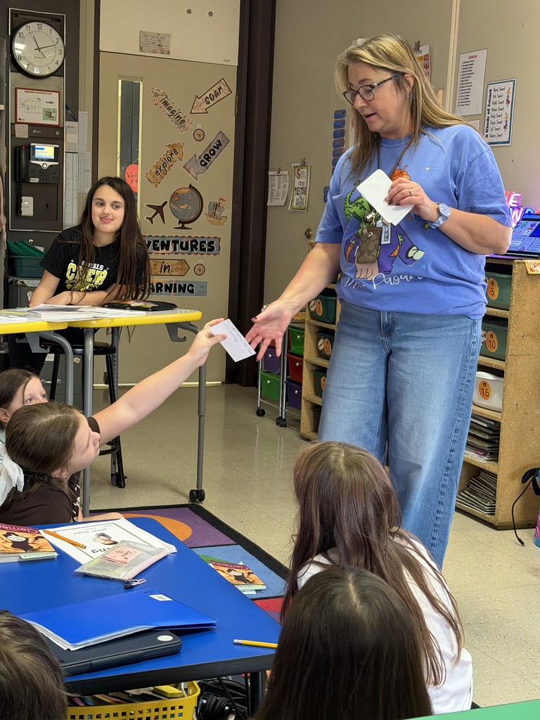 Mrs. Pagano collects a paper from a student. 