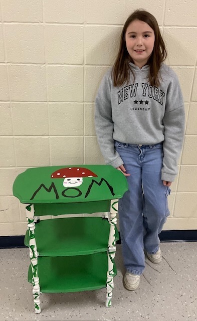 Female student posting with a mushroom themed shelf