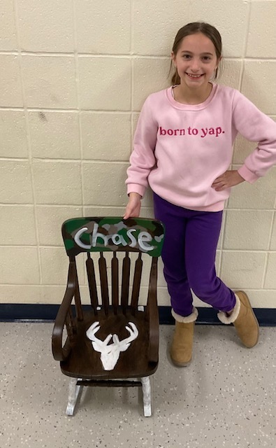 Female student posing with a camo chair