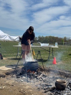student stirring large cooking pot