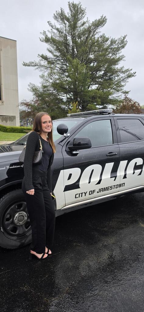 Female student standing near a police vehicle