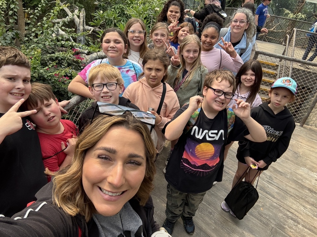 Students and teacher smiling in rainforest room at zoo