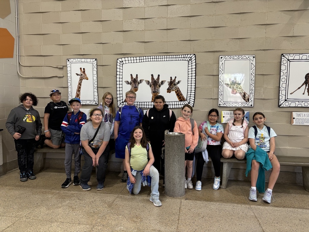 group of students smiling in giraffe house