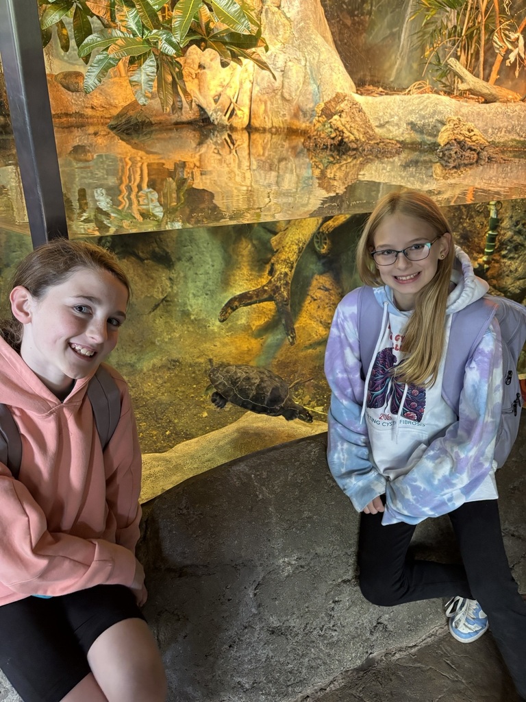 two girls smile in front of turtle tank