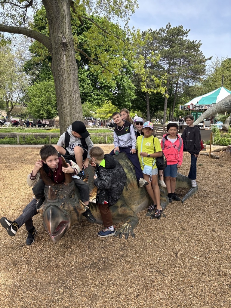 students pose on dino statue