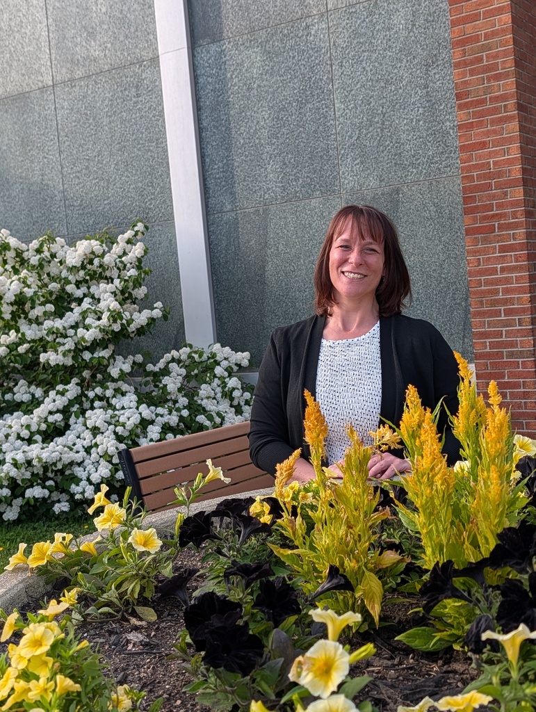 Mrs. Valentine smiling by flowers