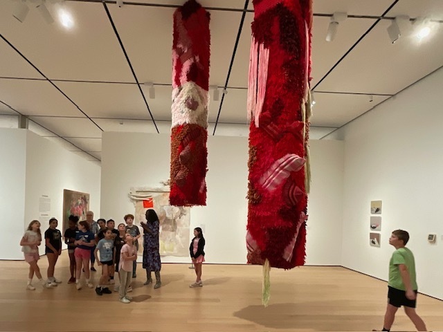 Students with hanging textile art. 