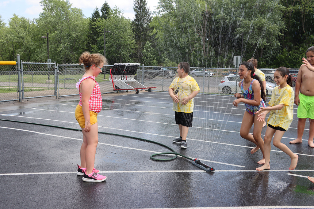 Students play in sprinkler. 