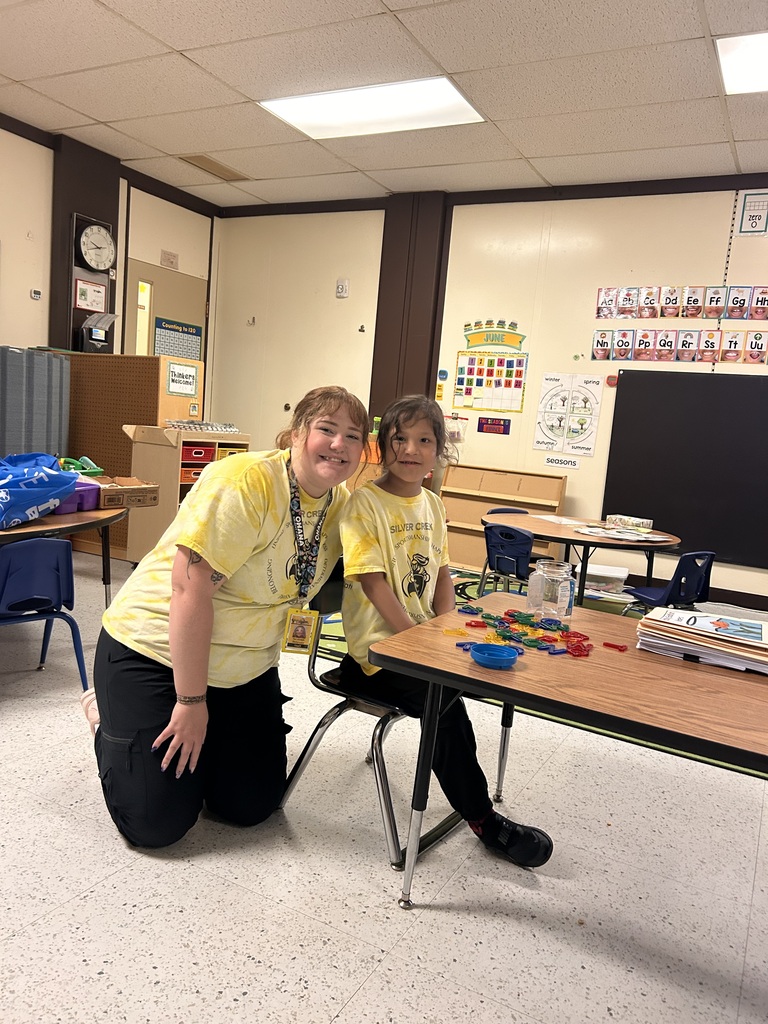 An adult and a student match in yellow t shirts and black pants