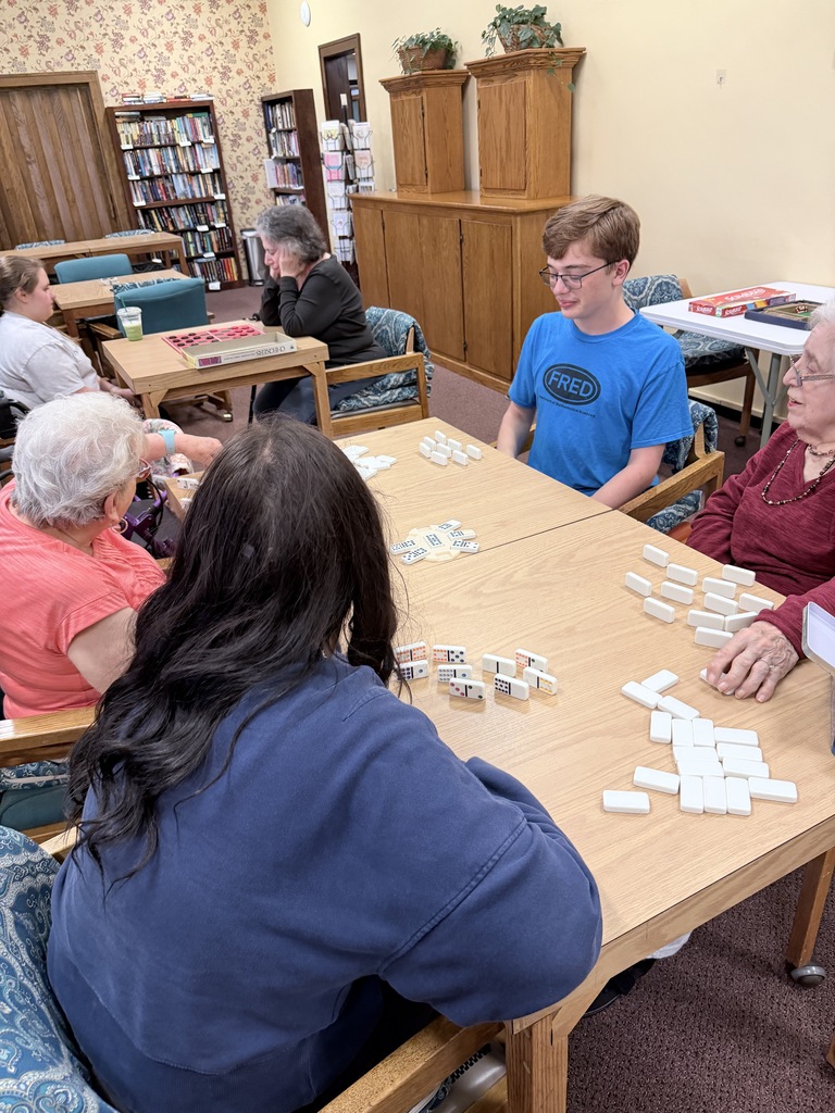 students play dominoes with senior residents