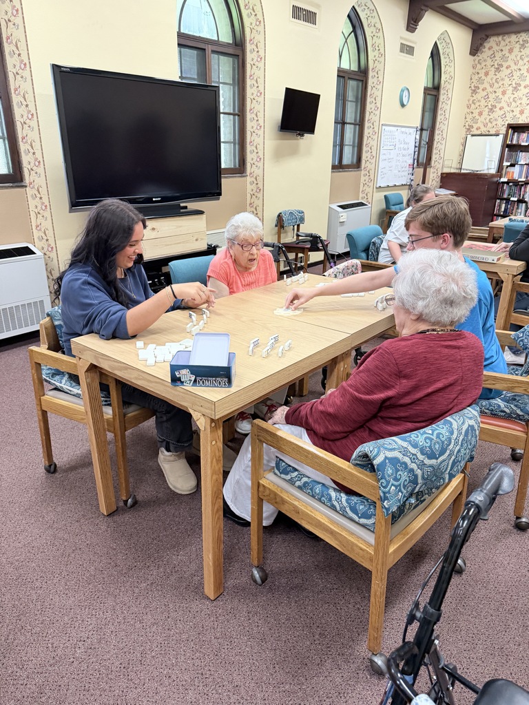 students play dominoes with senior residents